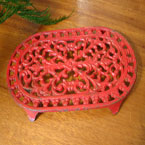 Antique cast iron trivet in red.